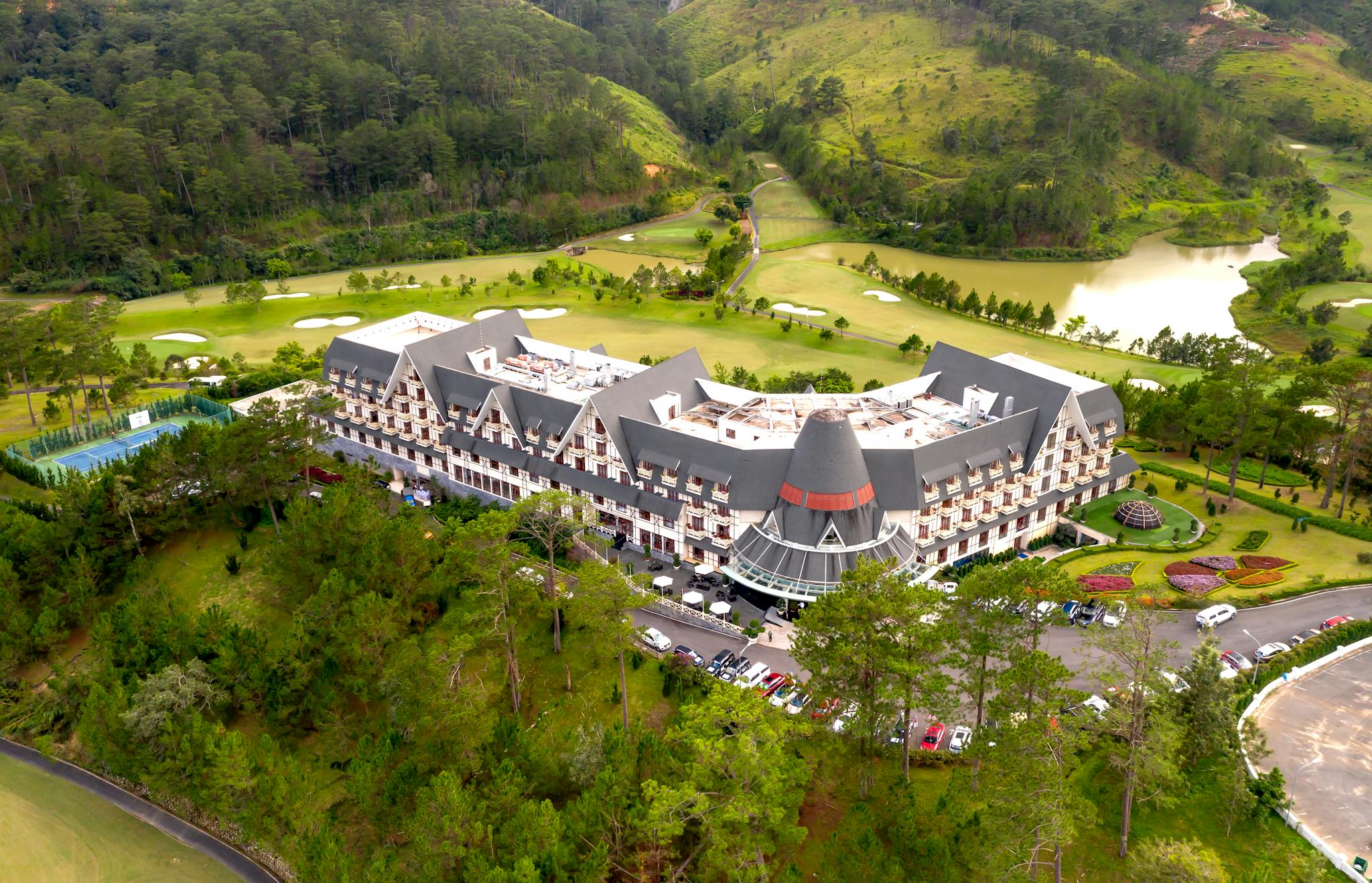 Aerial view of a sprawling luxury resort surrounded by lush greenery and hills.