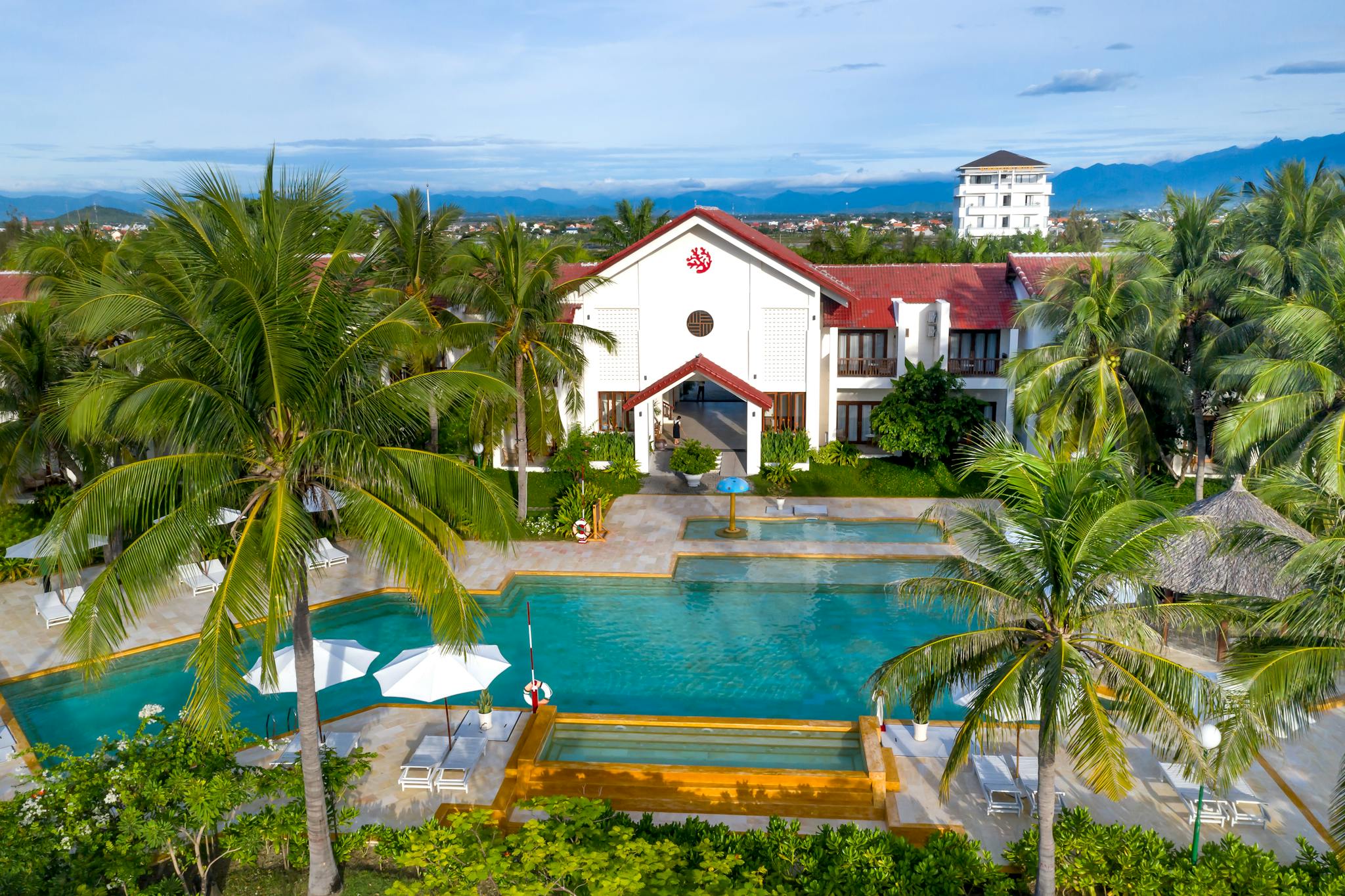 Aerial view of a tropical resort featuring a swimming pool and palm trees, perfect for relaxation.